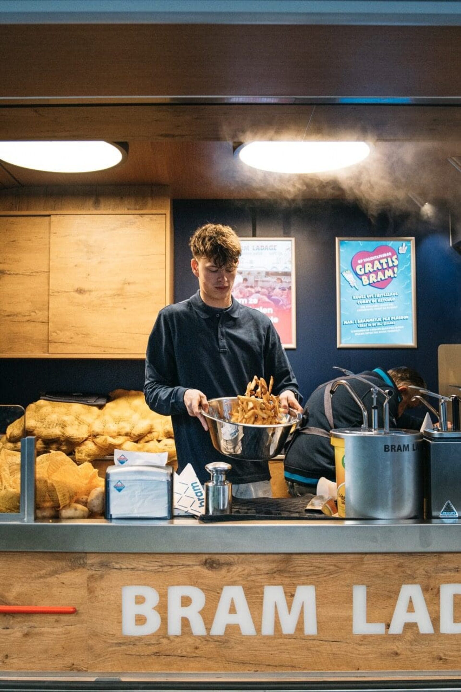 bram ladage medewerker met schaal patat in de brambus