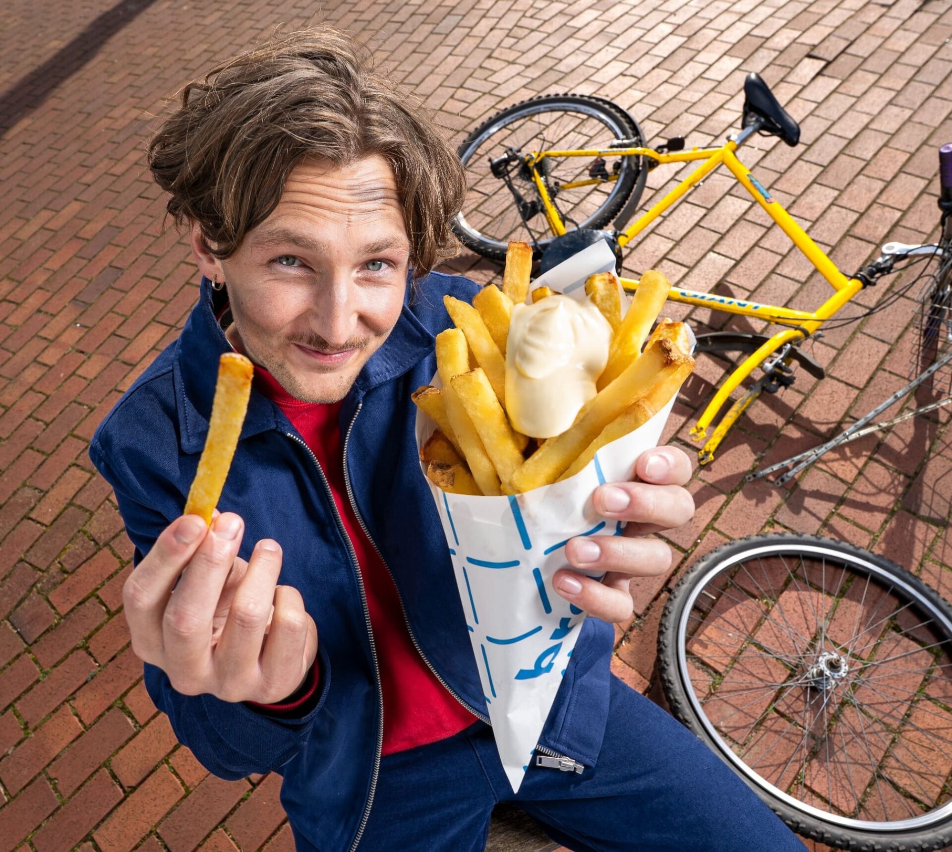 jonge man die blij naar zijn puntzak met patat kijkt
